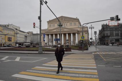 Москва.   Мужчина в медицинской маске переходит улицу у Театральной площади.