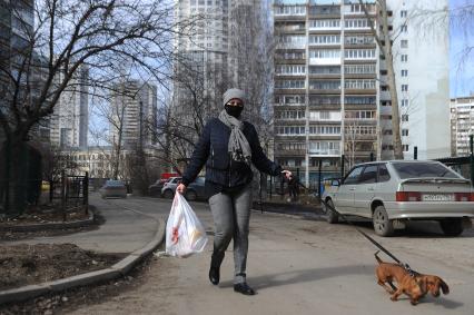 Екатеринбург. Женщина в медицинской маске гуляет с собакой во время нерабочей недели объявленной президентом РФ для снижения темпов распространения коронавируса COVID-19