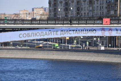 Москва.  Плакат с призывом соблюдать дистанцию от окружающих на Смоленском метромосту.