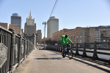 Москва.  Сотрудник службы доставки еды на улице города.