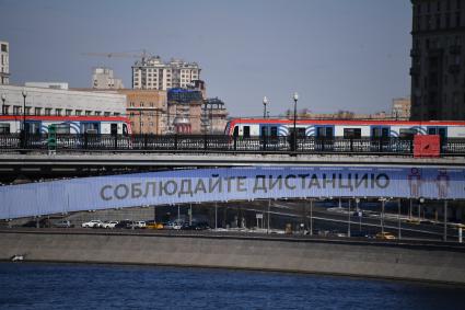 Москва.  Плакат с призывом соблюдать дистанцию от окружающих на Смоленском метромосту.