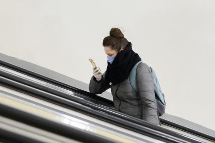 Санкт-Петербург. Женщина  в медицинской маске  на эскалаторе метрополитена.