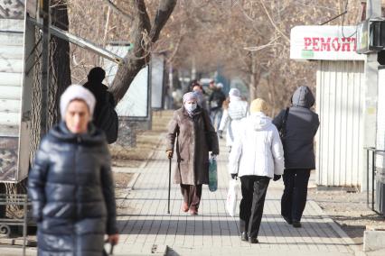 Иркутск.  Пожилая женщина в медицинской маске на улице.