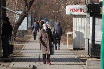 Иркутск.  Пожилая женщина в медицинской маске на улице.