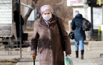 Иркутск.  Пожилая женщина в медицинской маске на улице.