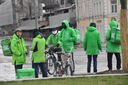 Москва. Сотрудники сервиса доставки еды на улице города.