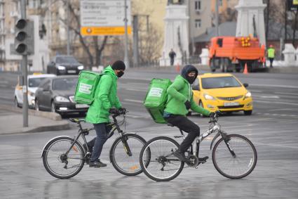 Москва. Сотрудники сервиса доставки еды на улице города.