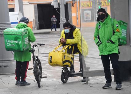 Москва. Сотрудники сервиса доставки еды на улице города.