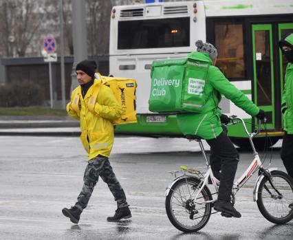 Москва. Сотрудники сервиса доставки еды на улице города.