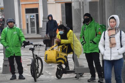 Москва. Сотрудники сервиса доставки еды на улице города.