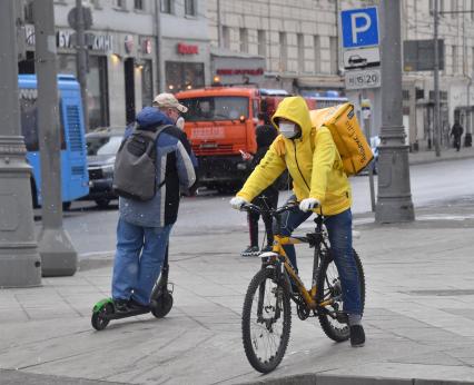 Москва. Сотрудники сервиса доставки еды на улице города.