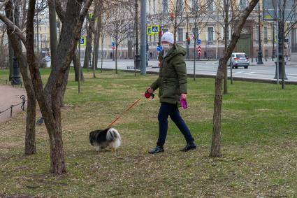 Санкт-Петербург. Женщина в медицинской маске выгуливает собаку.