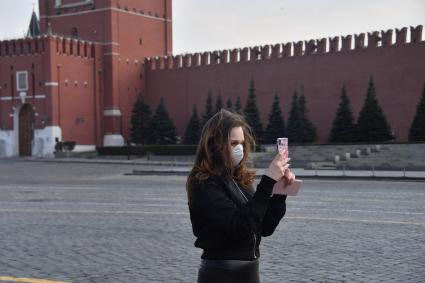 Москва.  Девушка в медицинской маске на Красной площади.