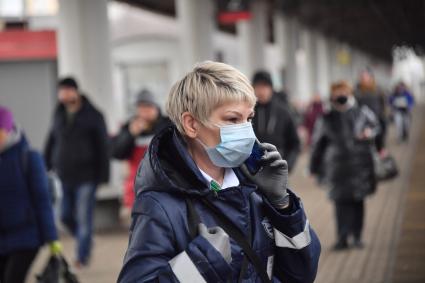 Москва.  Женщина в медицинской маске разговаривает по мобильному телефону.