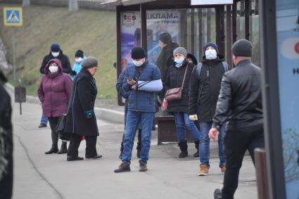 Москва.  Люди в медицинских масках на остановке общественного транспорта.