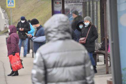 Москва.  Люди в медицинских масках на остановке общественного транспорта.