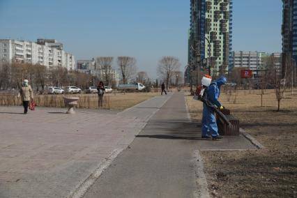 Красноярск. Сотрудник коммунальных служб обрабатывает антисептическим раствором  тротуары и скамейки.