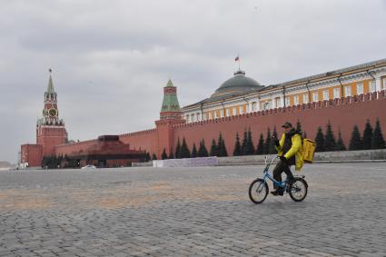 Москва. Сотрудник сервиса доставки еды `Яндекс. Еда`едет по Красной площади на велосипеде.