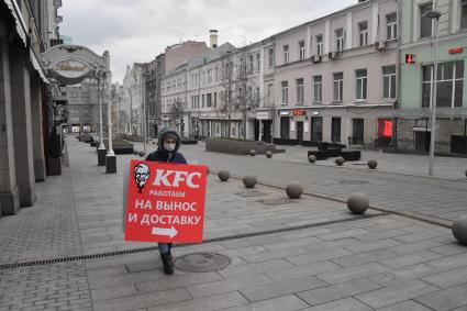 Москва. Мужчина в медицинской маске с плакатом кафе KFC.