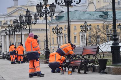 Москва. Сотрудники коммунальных служб красят скамейки на Манежной площади.