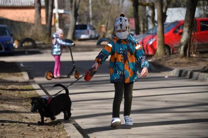 Москва.   Мальчик в медицинской маске гуляет с собакой во дворе.