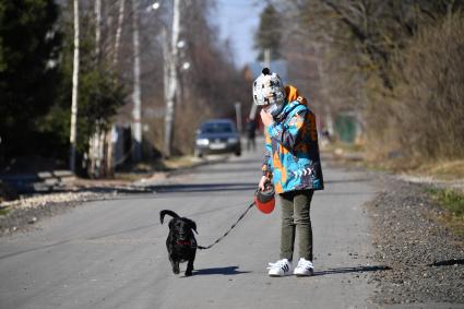 Москва.   Мальчик в медицинской маске гуляет с собакой во дворе.