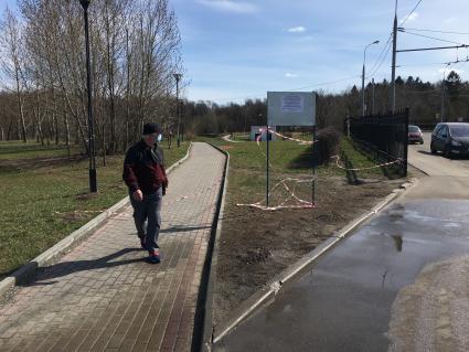 Москва. Мужчина в медицинской маске гуляет в закрытом парке.