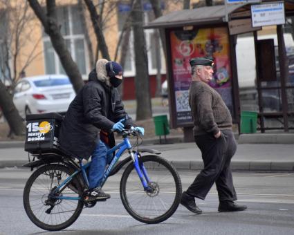 Москва. Сотрудник службы доставки еды в медицинской маске .