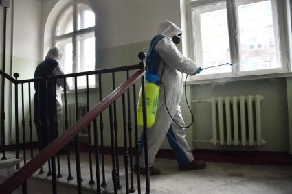 Москва. Сотрудник коммунальной службы в защитном костюме во время дезинфекции подъезда жилого дома.