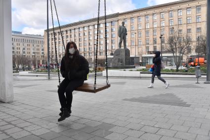 Москва. Девушка качается на качелях на Триумфальной площади.