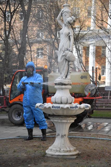 Москва.  Сотрудник коммунальной службы в защитном костюме во время дезинфекции улиц.