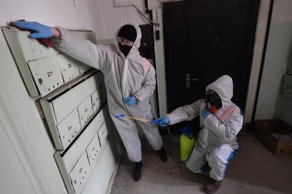 Москва. Сотрудник коммунальной службы в защитном костюме во время дезинфекции подъезда жилого дома.