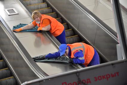 Москва. Сотрудники метрополитена дезинфицируют перила эскалатора.