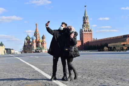 Москва. Молодой человек и девушка в медицинских масках фотографируются  на  Красной площади