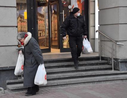 Москва. Пожилая женщина и мужчина выходят из магазина.