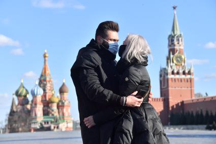 Москва. Молодой человек и девушка в медицинских масках фотографируются  на  Красной площади