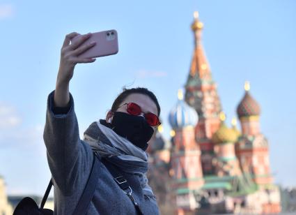 Москва. Девушка в медицинской маске делает селфи на Красной площади.