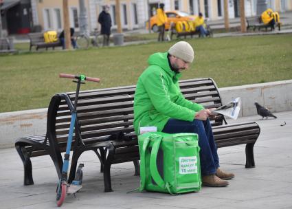 Москва. Сотрудник  сервиса доставки еды на улице города.