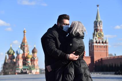 Москва. Молодой человек и девушка в медицинских масках целуются на  Красной площади