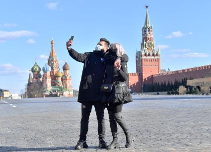 Москва. Молодой человек и девушка в медицинских масках фотографируются  на  Красной площади