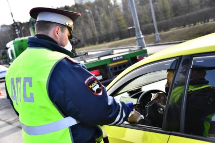 Москва. Сотрудник дорожно-патрульной службы ГИБДД во время проверки электронного пропуска у водителя на блокпосту при въезде в Москву.