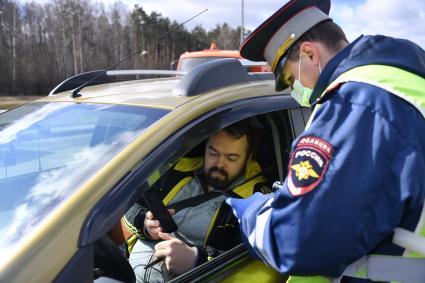 Москва. Сотрудник дорожно-патрульной службы ГИБДД во время проверки электронного пропуска у водителя на блокпосту при въезде в Москву.