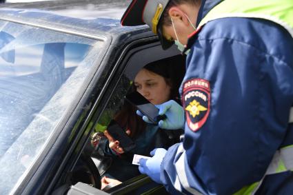 Москва. Сотрудник дорожно-патрульной службы ГИБДД во время проверки электронного пропуска у водителя на блокпосту при въезде в Москву.