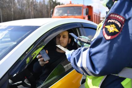 Москва. Сотрудник дорожно-патрульной службы ГИБДД во время проверки электронного пропуска у водителя на блокпосту при въезде в Москву.