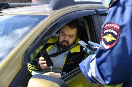 Москва. Сотрудник дорожно-патрульной службы ГИБДД во время проверки электронного пропуска у водителя на блокпосту при въезде в Москву.