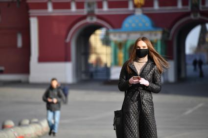 Москва. Девушка в защитной маске на Манежной площади.