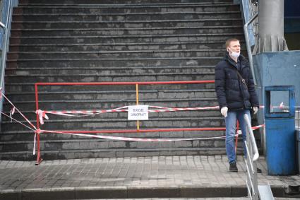 Москва.  Мужчина в медицинской маске  у закрытого входа.