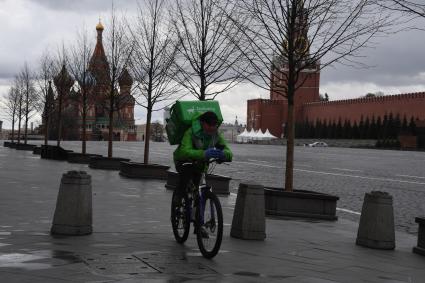 Москва.  Сотрудник сервиса доставки еды на Красной площади.