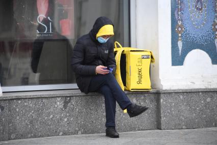 Москва.  Сотрудник сервиса доставки еды с мобильным телефоном.