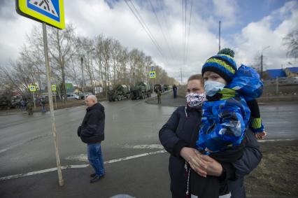 Екатеринбург. Женщина с ребенком в медицинских масках набдюдают за проведением репетиции парада.